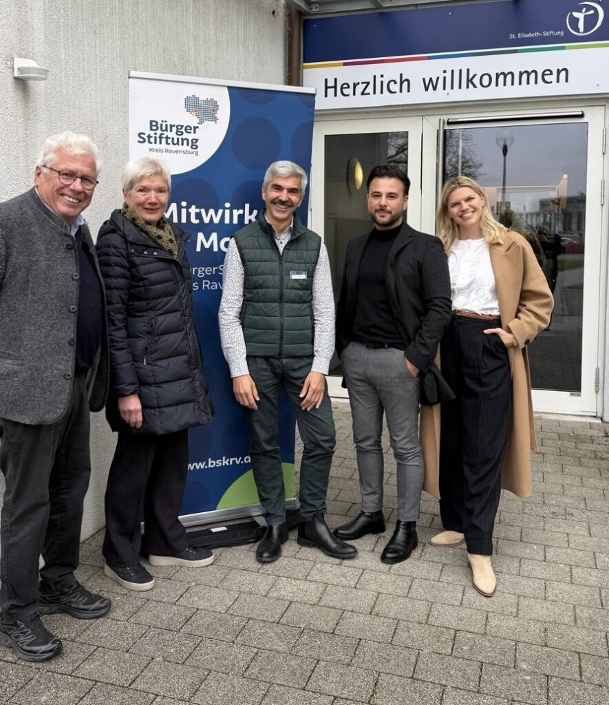 Gruppe von vier Personen steht vor Eingang eines Gebäudes