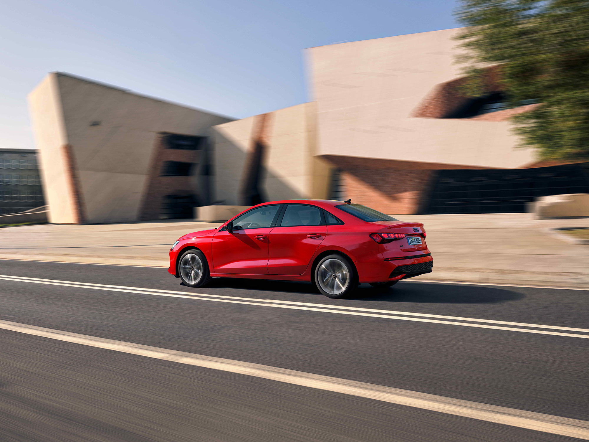 Rotes schnell fahrendes Auto auf einer Schnellstraße, braunes Gebäude im Hintergrund